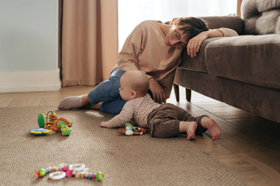 tired mom playing with baby on floor